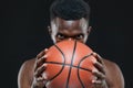 Close up front view shot of afro american male basketball player holding a ball in front of him over black background Royalty Free Stock Photo