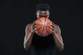 Close up front view shot of afro american male basketball player holding a ball in front of him over black background Royalty Free Stock Photo