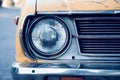 Close up and front view shot with copy space of chrome grill and front light of yellow retro car in grunge condition with rust and Royalty Free Stock Photo