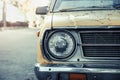 Close up and front view shot with copy space of chrome grill and front light of yellow retro car in grunge condition with rust and Royalty Free Stock Photo