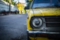 Close up and front view shot with copy space of chrome grill and front light of yellow retro car in grunge condition with rust and Royalty Free Stock Photo