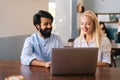 Close-up front view of two multiracial smiling creative workers discussing project during meeting in cafe. Royalty Free Stock Photo