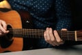 Close-up front view of unrecognizable guitarist male playing acoustic guitar sitting at desk in dark living room Royalty Free Stock Photo