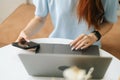 Close-up front view of unrecognizable young woman in smart watch using laptop and phone sitting at table in cafe with Royalty Free Stock Photo