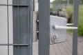 A close-up front view of the white handle on the steel fence gate.