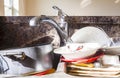 Close up frontal view of a kitchen mess with dirty pots, dishes and utensils have piled up in kitchen sink i