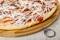 Close up of frozen pizza with sausage, tomato and cheese on cutting board on table Royalty Free Stock Photo