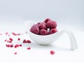 Close up of frozen rasberries in a white bowl on a white background with selective focus.