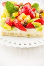 Close-up of fruit tart with strawberries, mango and kiwi, on a white plate, white table, vertical, Royalty Free Stock Photo