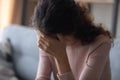 Close up frustrated depressed woman touching forehead, sitting alone