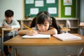 Close up frustrated unhappy little schoolgirl studying in classroom at school during lesson, bored and discouraged student. School Royalty Free Stock Photo