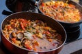 Close-up of frying pans with seafood dish cooked in tomato sauce. Fresh stewed Clams, Shrimps, mussels and squid, base Royalty Free Stock Photo