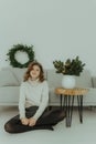 Close up fun cool smiling young girl with Christmas wreath on workspace area isolated on plain light background New Year