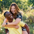 Happy diverse couple doing piggybacking outdoors