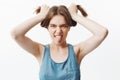 Close up of funny attractive caucasian young student girl looking in camera, showing tongue, making silly faces, having