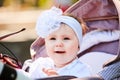 Close-up of the funny baby girl sitting in the stroller and holds sunglasses. Royalty Free Stock Photo