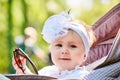 Close-up of the funny baby girl sitting in the stroller and holds sunglasses. Royalty Free Stock Photo