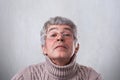 A close-up of funny grandfather in glasses looking happily through eyeglasses having fun. An elderly man having mysterious express