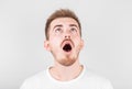 Close up of funny handsome young man with in stylish white t-shirt looking in camera with raised eyebrows and surprised face