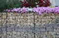 Close-up of a gabion support wall with wire mesh reinforcement topped with pebbles and tiles Royalty Free Stock Photo