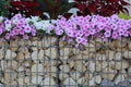 Close-up of a gabion support wall with wire mesh reinforcement topped with pebbles and tiles Royalty Free Stock Photo