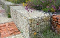 Close-up of a gabion support wall with wire mesh reinforcement topped with pebbles and tiles Royalty Free Stock Photo