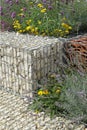 Close-up of a gabion support wall with wire mesh reinforcement topped with pebbles and tiles Royalty Free Stock Photo