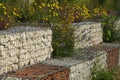 Close-up of a gabion support wall with wire mesh reinforcement topped with pebbles and tiles Royalty Free Stock Photo