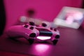 Close-up of gaming controller laying on table in purple illuminated room. Selective focus Royalty Free Stock Photo