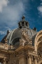 Close-up of garish decoration in the dome and arch gate of the Petit Palais on sunny day in Paris.