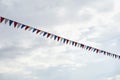 Close-up garland of multi colored flags of triangular shape, pennants in blue sky. Modern background, banner design