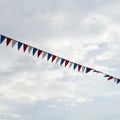 Close-up garland of multi colored flags of triangular shape, pennants in blue sky. Modern square background, banner