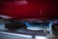 Close up gas stove with blue flames of burning gas with red pan Royalty Free Stock Photo