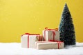 Gift boxes, Christmas tree on table and yellow background. Royalty Free Stock Photo