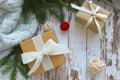 Close - up of gift boxes with white ribbon on wooden textured white background surrounded by green spruce branches and toys. Royalty Free Stock Photo