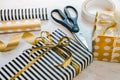 Close up of gift boxes wrapped in black and white striped and golden dotted paper and wrapping materials on a white wood old backg Royalty Free Stock Photo