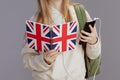 Closeup on girl with backpack, english flag workbook, headphones and smartphone against grey