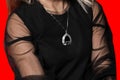 Close-up of girl in black translucent dress on her arms and a pendant around the neck, fashion and style of clothing on red