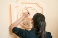 Close up of a girl (dark hair and black clothes) decorating a wall with a floral motive element with a brush Royalty Free Stock Photo