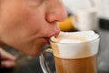 Close-up of a girl drinking from a glass cup of coffee foam and milk prepared in a coffee machine Royalty Free Stock Photo