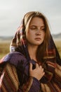 close-up. a girl in an ethno cape with a sad face holds a hand cape thrown zero on her head and shoulders Royalty Free Stock Photo