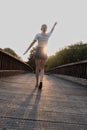 Close-up of girl exercising on wooden bridge. Tranquility at sunset