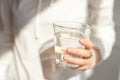 Close-up girl hands in the office stands in the sunlight holding a glass of clean water in between work. Royalty Free Stock Photo