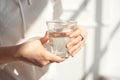 Close-up girl hands in the office stands in the sunlight holding a glass of clean water in between work. Royalty Free Stock Photo