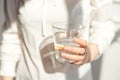 Close-up girl hands in the office stands in the sunlight holding a glass of clean water in between work. Royalty Free Stock Photo