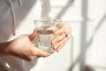 Close-up girl hands in the office stands in the sunlight holding a glass of clean water in between work. Royalty Free Stock Photo