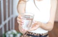 Close-up girl hands in the office stands in the sunlight holding a glass of clean water in between work Royalty Free Stock Photo