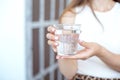 Close-up girl hands in the office stands in the sunlight holding a glass of clean water in between work Royalty Free Stock Photo