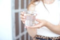 Close-up girl hands in the office stands in the sunlight holding a glass of clean water in between work Royalty Free Stock Photo