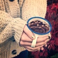 Close-up on girl hands with sweater holding a hot chocolate